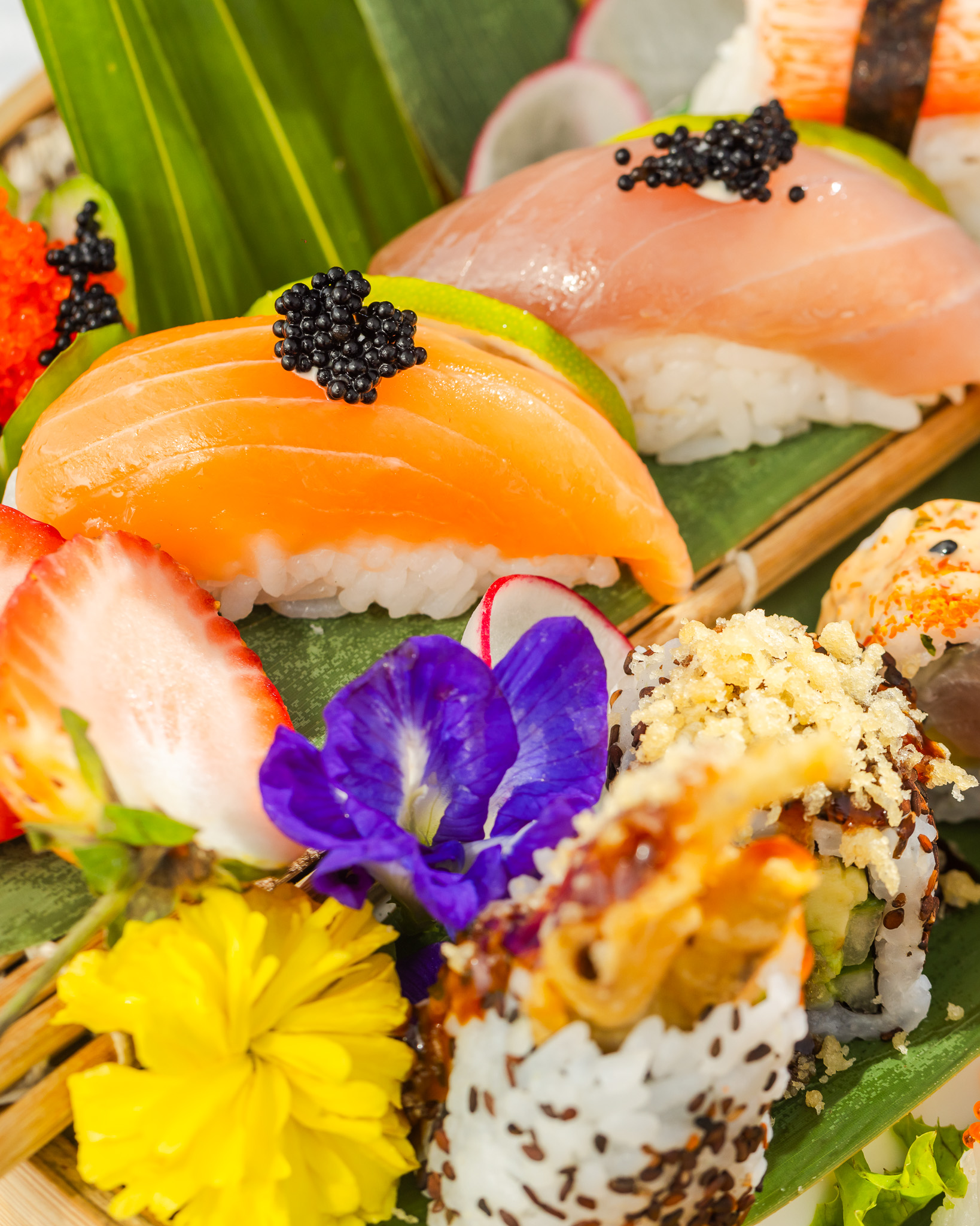 Sushi platter with salmon nigiri, caviar and edible flowers in yellow and purple